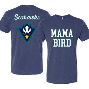May include: Two navy blue t-shirts. One features the text "MAMA BIRD" in white block letters. The other shirt has the word "Seahawks" in white script on the back, above a teal, white, and yellow logo.