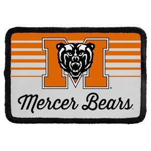 May include: A rectangular patch with a black stitched border featuring an orange and white striped background. A large orange letter M is centered with a black and white bear head graphic inside. The text Mercer Bears is printed in black script.