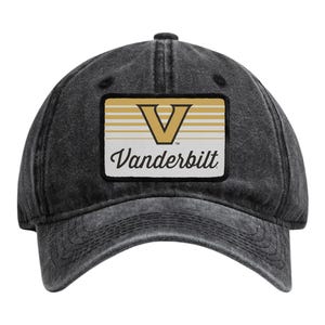 May include: A charcoal grey washed cotton baseball cap featuring a rectangular patch on the front. The patch displays a gold letter V above horizontal gold stripes and the word Vanderbilt in black script text against a white background.