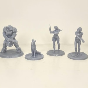 May include: Four gray miniature figurines. A heavily armored figure with a weapon, a dog, and two female figures with weapons. The figures are on circular bases, suggesting they are for a tabletop game or display.