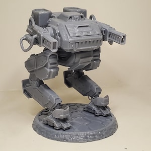 Könnte beinhalten: Ein graues Miniatur-Mech-Roboter-Modell mit detaillierten mechanischen Merkmalen, einschließlich Cockpit, Kanonen und gelenkigen Beinen. Das Modell steht auf einer kreisförmigen Basis und zeigt ein futuristisches Design. Die Gesamtästhetik deutet auf ein Science-Fiction- oder Gaming-Thema hin.