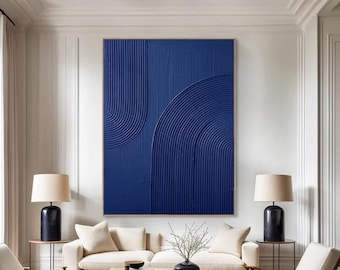May include: A large abstract painting with a blue background and white lines. The painting is hanging on a white wall in a living room with a white couch and two chairs.