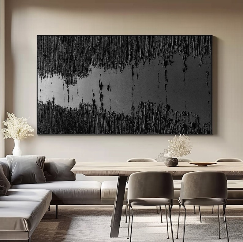 Puede incluir: Una pintura abstracta en blanco y negro con una superficie texturizada. La pintura est&aacute; enmarcada y colgada en una pared de una sala de estar moderna.