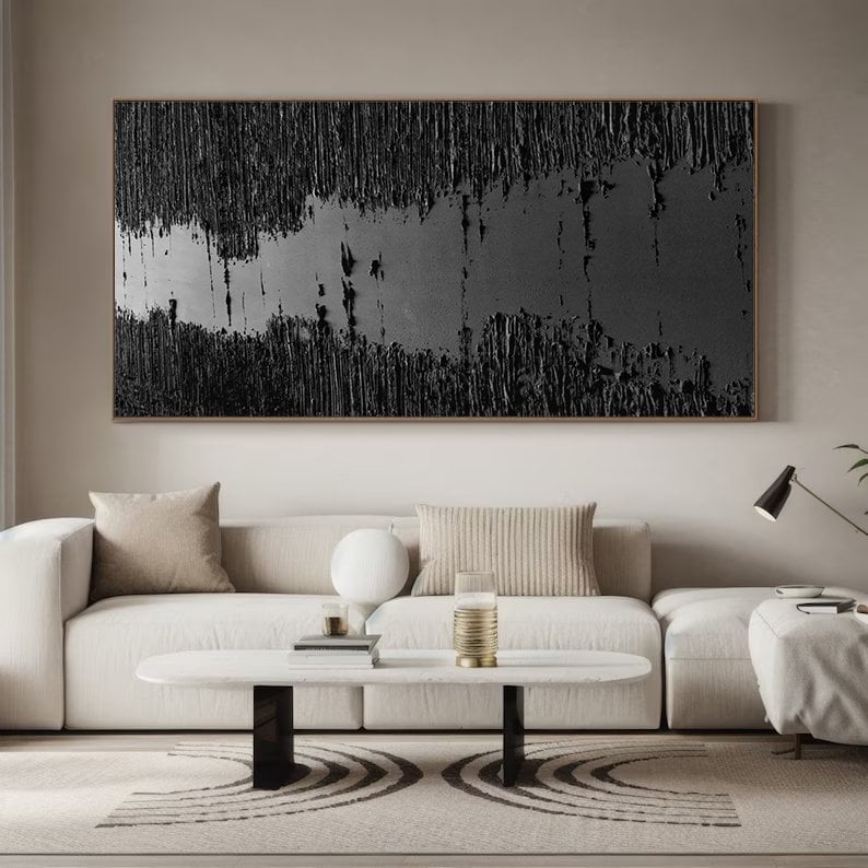 Puede incluir: Una pintura abstracta en blanco y negro cuelga sobre un sof&aacute; seccional blanco con almohadas beige. El sof&aacute; est&aacute; en una sala de estar con una mesa de caf&eacute; blanca y una alfombra en blanco y negro.