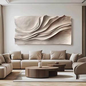 May include: A large, abstract wall art piece with a layered, wave-like design in neutral beige tones. The artwork hangs above a beige sectional sofa, complementing the room's modern, minimalist aesthetic. The room also features two round coffee tables and a vase with dried plants.