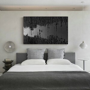 Puede incluir: Un dormitorio con un dise&ntilde;o moderno que presenta una cama gris con ropa de cama blanca y una pintura abstracta en blanco y negro en la pared. La habitaci&oacute;n tiene una cabecera gris y dos almohadas grises.