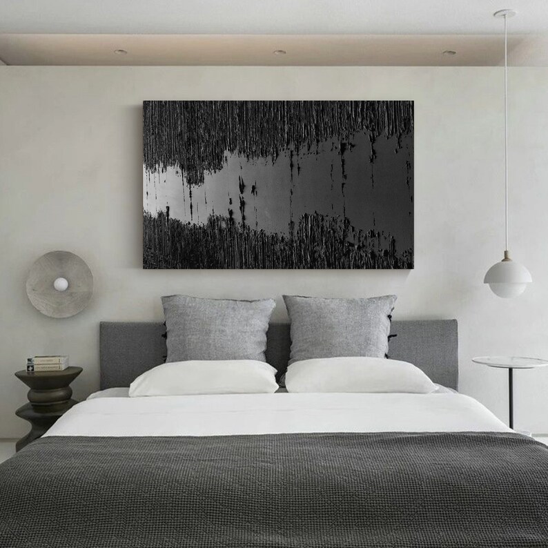 Puede incluir: Un dormitorio con un dise&ntilde;o moderno que presenta una cama gris con ropa de cama blanca y una pintura abstracta en blanco y negro en la pared. La habitaci&oacute;n tiene una cabecera gris y dos almohadas grises.