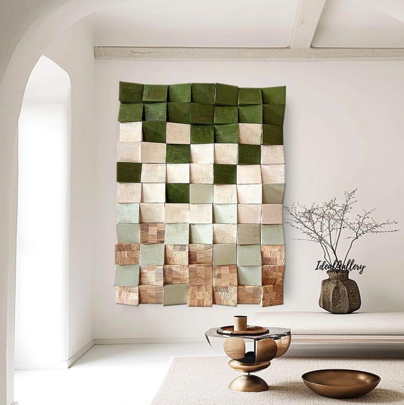 May include: A green, beige, and brown wooden wall art piece with a geometric pattern. The art piece is hanging on a white wall in a room with a white couch and a gold metal table. The text 'Ideal Gallery' is visible in the bottom right corner of the image.