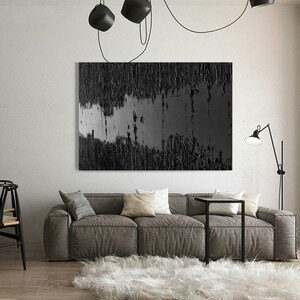 Puede incluir: Una pintura abstracta en blanco y negro con l&iacute;neas verticales y una banda horizontal gris en el medio. La pintura est&aacute; colgada en una pared blanca en una sala de estar moderna.