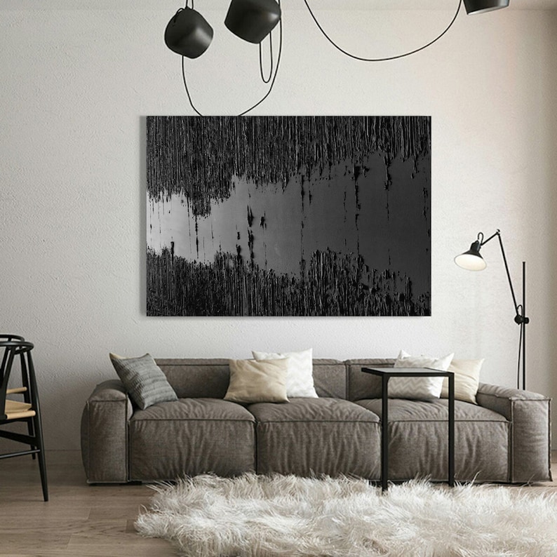 Puede incluir: Una pintura abstracta en blanco y negro con l&iacute;neas verticales y una banda horizontal gris en el medio. La pintura est&aacute; colgada en una pared blanca en una sala de estar moderna.