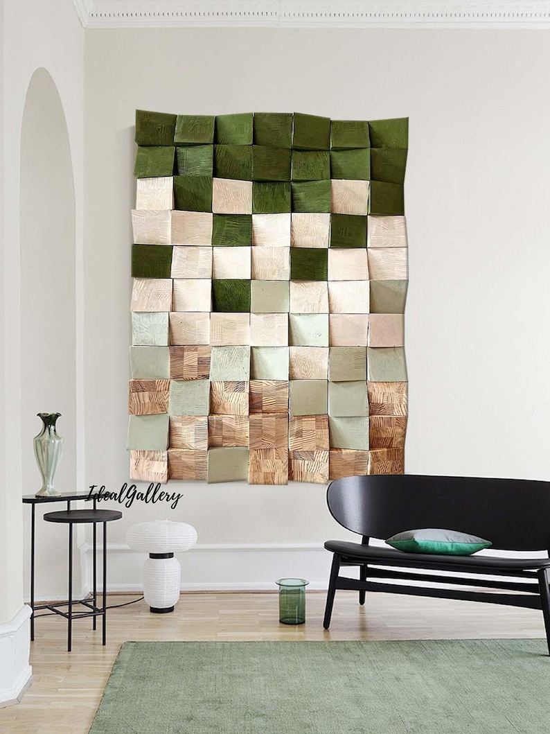 May include: A wall art piece made of wood squares in shades of green, beige, and brown. The squares are arranged in a grid pattern and have a 3D effect. The art piece is hanging on a white wall in a living room setting.