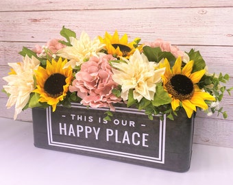 May include: A black metal planter with a white inscription that reads "This is our Happy Place" filled with a floral arrangement of sunflowers, pink hydrangeas, and white dahlias.