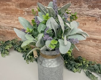 May include: A bouquet of faux lavender and lambs ear in a galvanized metal milk can with a wooden handle.
