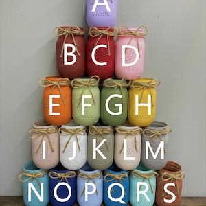 May include: A set of 15 mason jars painted in various colours, arranged in a pyramid shape. The jars are labelled with the letters A through S.