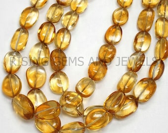 May include: Strands of polished, oval-shaped citrine gemstone beads. The translucent, golden-yellow stones are strung together, showcasing their natural color and clarity. The beads are smooth and have a glossy finish, ideal for jewelry making.