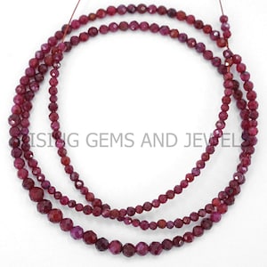 Peut inclure: Trois rangées de perles de pierres précieuses rubis facettées de tailles variables. Les perles sont d'un rouge profond et enfilées sur un fil fin et sombre. L'image est d'un produit de bijouterie.