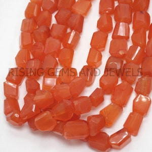 Könnte beinhalten: Eine Strähne orangefarbener Karneolperlen, jede Perle ist facettiert und hat eine leicht unregelmäßige Form. Die Perlen sind auf einem durchsichtigen Faden aufgereiht.