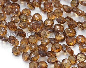 May include: A close-up of numerous faceted, amber-coloured gemstone beads. The beads are round with a polished surface, suitable for jewellery. The colour varies from light to dark amber. The beads are strung together, ready for use.