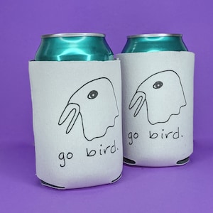 May include: Two white can coolers with a black and white illustration of a bird with the text "go bird." printed on them.