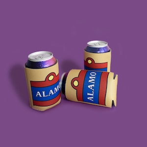 May include: Three aluminum cans in brown and blue Alamo can coolers, set against a purple background. The coolers have a red and blue design with the word "ALAMO" in white. The cans have silver lids and glittery purple and blue contents.