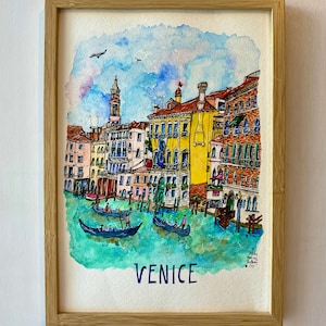 May include: A watercolor painting of a canal in Venice, Italy. The painting features colorful buildings, gondolas, and a blue sky with white clouds. The text "VENICE" is written in blue at the bottom of the painting.