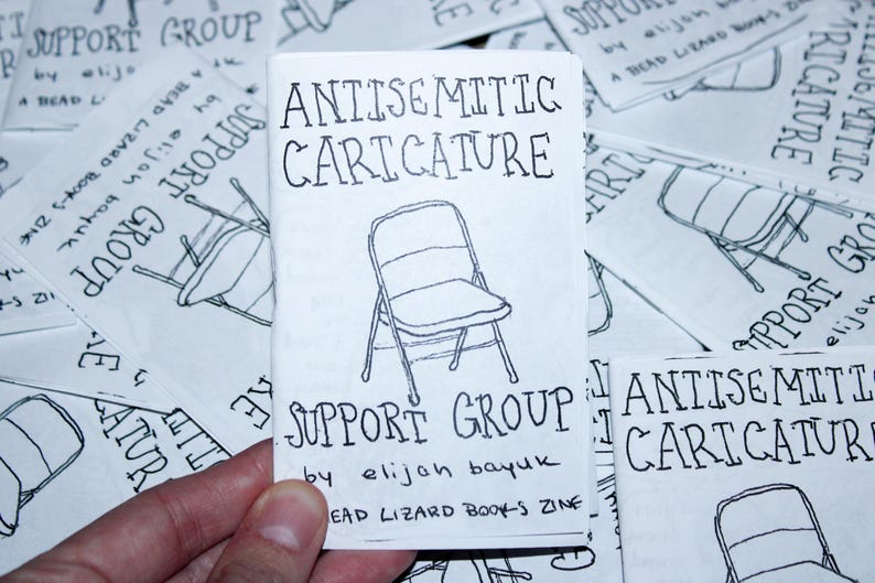 K&ouml;nnte beinhalten: Ein kleines, wei&szlig;es Zine mit dem Titel "Antisemitic Caricature" und einer handgezeichneten Stuhllustration. Der Text "Support Group" und der Name des Autors sind ebenfalls sichtbar. Andere Zines mit &auml;hnlichen Designs sind im Hintergrund.