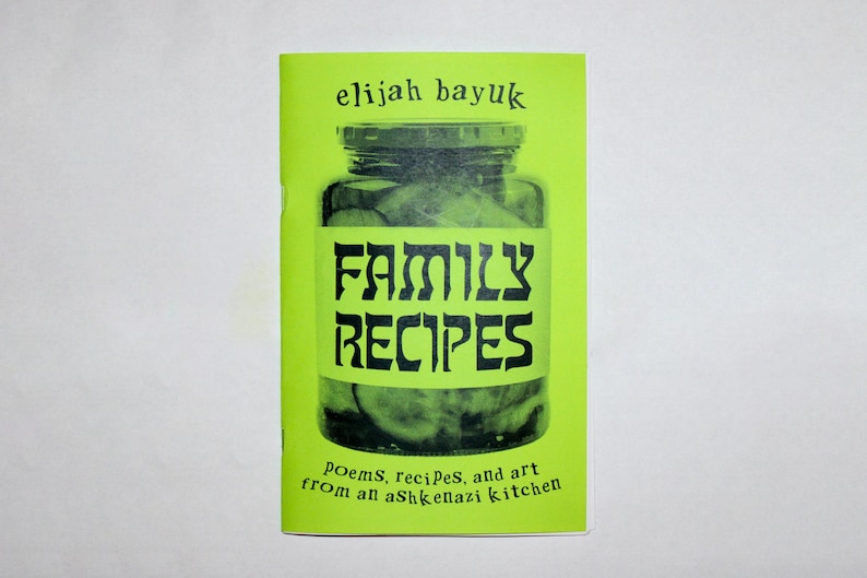 Puede incluir: Un peque&ntilde;o libro verde lima titulado "Family Recipes" con el nombre del autor, elijah bayuk, en la parte superior. La portada presenta un tarro de pepinillos y el texto "FAMILY RECIPES" en letras negras en negrita. La parte inferior del libro dice "Poems, recipes, and art from an Ashkenazi kitchen."