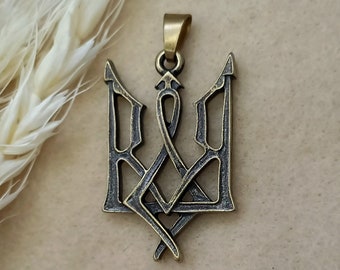 May include: A gold-toned metal pendant in the shape of the Ukrainian trident, a traditional symbol of Ukraine.
