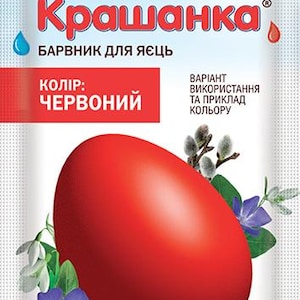 Könnte beinhalten: Eine Packung rote Eierfarbe mit ukrainischem Text "UKRASA Крашанка" und "Made in Ukraine". Das Design zeigt ein großes rotes Ei, Blumen und Zweige.