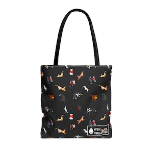 K&ouml;nnte beinhalten: Schwarze Tragetasche mit einem sich wiederholenden Muster von Hunden, die mit Frisbees spielen. Die Tasche hat schwarze Griffe und ein wei&szlig;es Logo mit der Aufschrift "WET LAB CREATIVE".