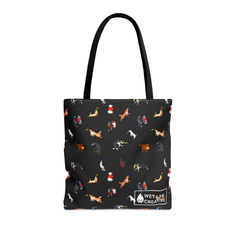 K&ouml;nnte beinhalten: Schwarze Tragetasche mit einem sich wiederholenden Muster von Hunden, die mit Frisbees spielen. Die Tasche hat schwarze Griffe und ein wei&szlig;es Logo mit der Aufschrift "WET LAB CREATIVE".
