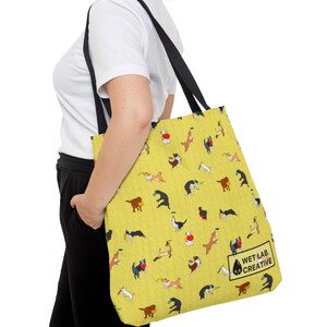 K&ouml;nnte beinhalten: Gelbe Tragetasche mit einem sich wiederholenden Muster von verspielten Hunden in verschiedenen Posen. Die Tasche hat schwarze Tr&auml;ger und den Text "WET LAB CREATIVE". Die Tasche wird &uuml;ber der Schulter getragen.