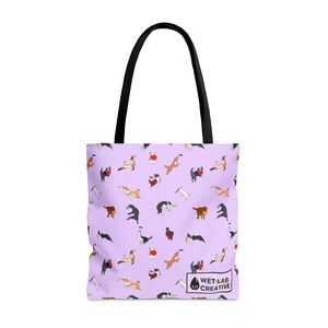 K&ouml;nnte beinhalten: Tragetasche mit hellviolettem Hintergrund und einem sich wiederholenden Muster von spielerischen Hundeillustrationen in verschiedenen Posen. Die Tasche hat schwarze Griffe und den Text "WET LAB CREATIVE" unten rechts.