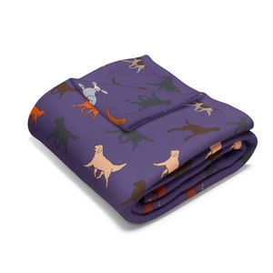 Peut inclure: Une couverture violette pliée avec un motif répété de différentes races de chiens de différentes couleurs. Les chiens sont représentés dans un style ludique et caricatural. La couverture est pliée proprement, mettant en valeur le motif.