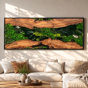 May include: A rectangular wall art piece featuring two horizontal slabs of natural wood with a dark grain, framing a central section filled with vibrant green preserved moss, dark green leaves, and small white flowers, all enclosed in a black frame.