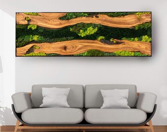 Peut inclure: Une œuvre d'art murale rectangulaire en bois avec un cadre noir. L'œuvre présente deux sections en bois brun clair et fluides avec de la mousse et des plantes vertes entre elles. L'œuvre est au-dessus d'un canapé gris.