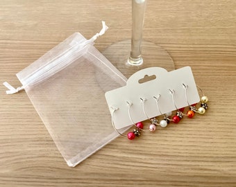 May include: Set of five wine glass charms with silver hoops and colorful beads. The charms are packaged on a white card with a hole for hanging. The charms are also packaged in a white organza bag.