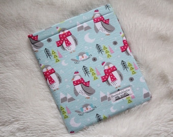 May include: A light blue fabric pouch with a penguin pattern. The penguins are wearing red scarves and hats. The pouch has a white label with the text "Boehnerwdidlae".