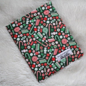 May include: A green book sleeve with a Christmas candy cane and lollipop pattern. The sleeve has the text "Booknerdchic" printed on it.
