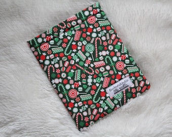 May include: A green book sleeve with a Christmas candy cane and lollipop pattern. The sleeve has the text "Booknerdchic" printed on it.