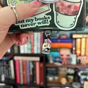 May include: Clear phone case with stickers, including a coffee cup with hearts and the text "but my books never will!". A small charm with a jar design and the words "ANTI DEPRESSANTS" is attached.