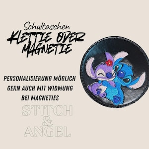 Könnte beinhalten: Ein schwarzer runder Aufnäher mit einem gestickten Bild von zwei Zeichentrickfiguren, einer blauen und einer lila, die sich umarmen. Der Aufnäher hat deutschen Text, einschließlich "STITCH & ANGEL".