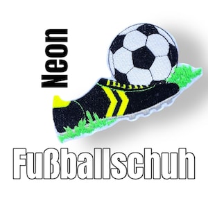 Könnte beinhalten: Schwarzer und gelber Fußballschuh mit einem weißen und schwarzen Fußball darauf. Der Schuh befindet sich auf einem grünen Grasfleck. Der Text "Neon" ist vertikal auf der linken Seite des Bildes geschrieben. Der Text "Fußballschuh" ist horizontal am unteren Rand des Bildes geschrieben.