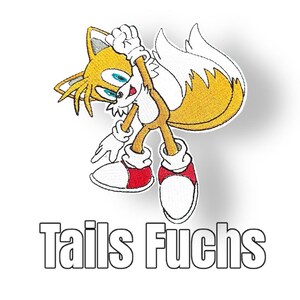 Könnte beinhalten: Ein gestickter Aufnäher mit Tails, einem gelben Fuchscharakter aus der Videospielserie Sonic the Hedgehog. Tails ist mit seinen zwei Schwänzen dargestellt, trägt weiße Handschuhe und rote Schuhe, und der Text "Tails Fuchs" befindet sich unter dem Bild.
