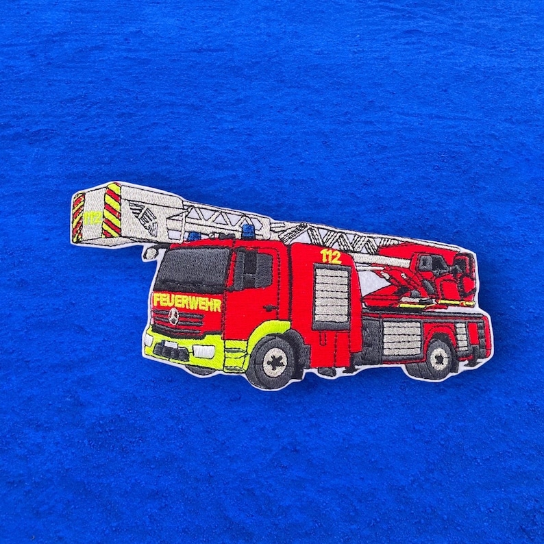 May include: Red and white fire engine with a ladder, the words "FEUERWEHR" and "112" are on the side of the engine.