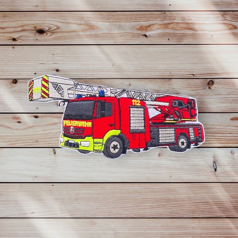 May include: Red and white embroidered patch of a fire engine with a ladder, the words "FEUERWEHR" and "112" are visible on the truck.