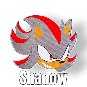 Könnte beinhalten: Gestickter Aufnäher mit der Figur Shadow aus der Sonic the Hedgehog-Serie. Der Aufnäher zeigt Shadows graues Fell, rote Akzente und einen entschlossenen Gesichtsausdruck. Das Wort "Shadow" ist in fetten, weißen Buchstaben dargestellt.