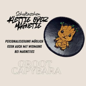 Könnte beinhalten: Ein runder, schwarzer Aufnäher mit einem gestickten Groot-Motiv. Der Aufnäher hat ein braunes Groot-Design mit grünen Blättern und den Texten "Schultaschen Klettie oder Magnetie" und "Groot Capybara".