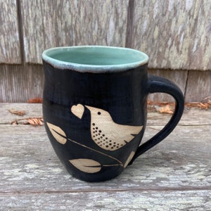 Taza con diseño de pájaro hecha a mano: cerámica de arte popular en blanco y negro.