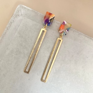 May include: A pair of gold earrings with long, rectangular, open-work dangles and colorful, square, resin tops.